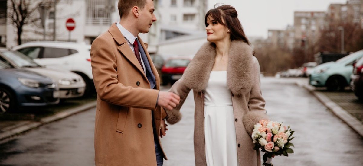 a man and a woman holding hands on a city street